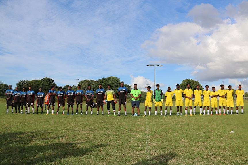 Two soccer teams lined up on the field. 