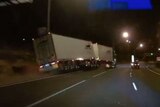 Trailers of a semi-trailer sway on a dark freeway