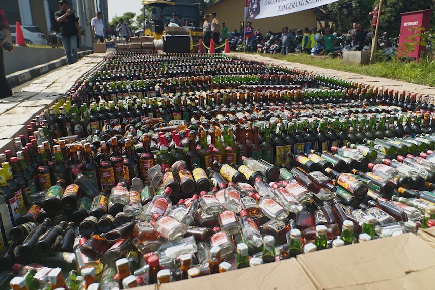 Wide shot of dozens of long rows of multi-coloured glass bottles.