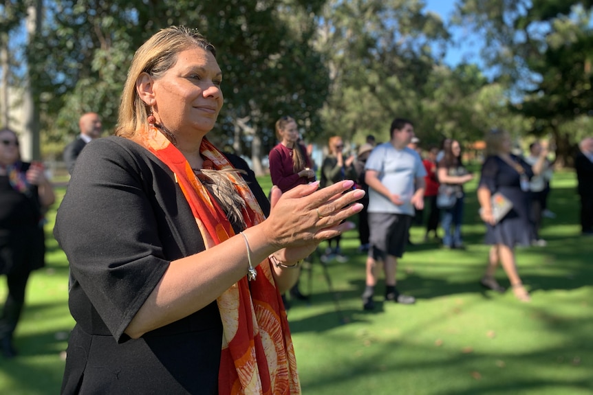 An Indigenous woman in a park clapping