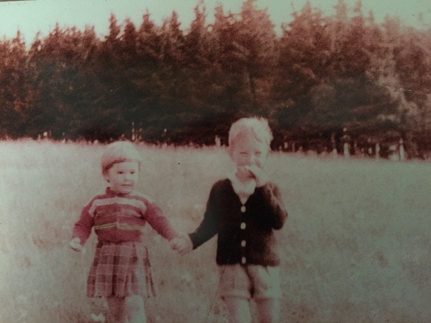 an old photo of a young boy and young girl hold hands in a field