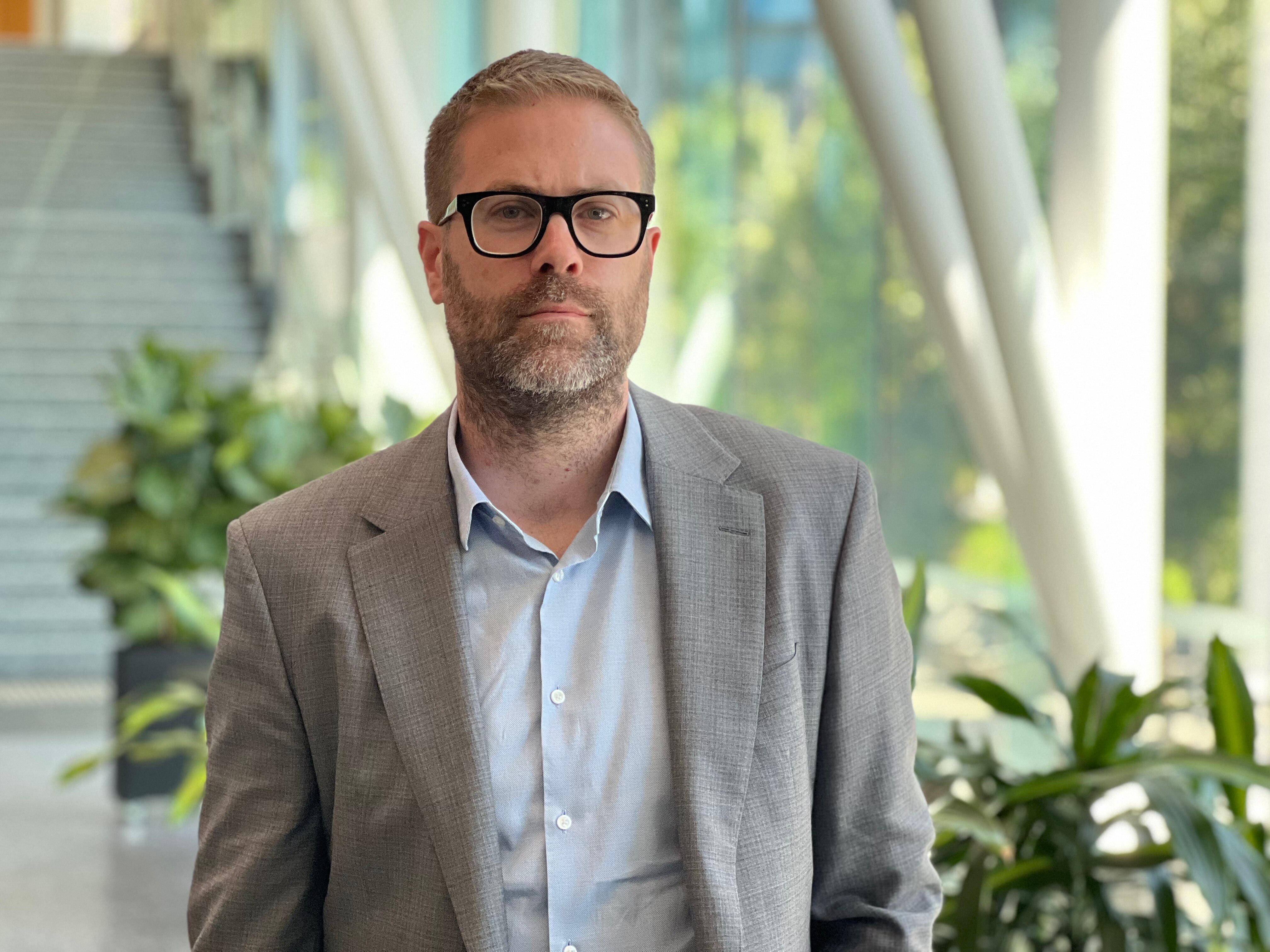 A man wearing glasses looks sternly at the camera