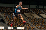 Matthew Clarke jumps over a steeple in a race with an empty stand in the background.