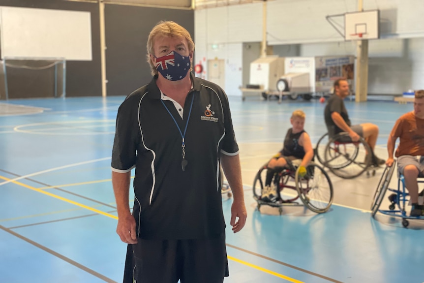 Man in Aus flag face mask stands on a basketball court 