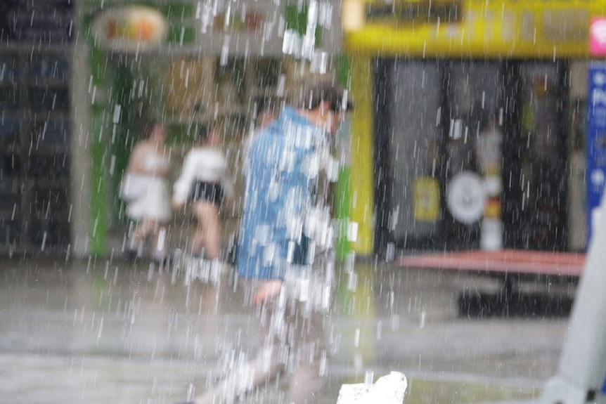 Heavy rain masks man walking in the Queen Street Mall in Brisbane's CBD on February 2, 2021.