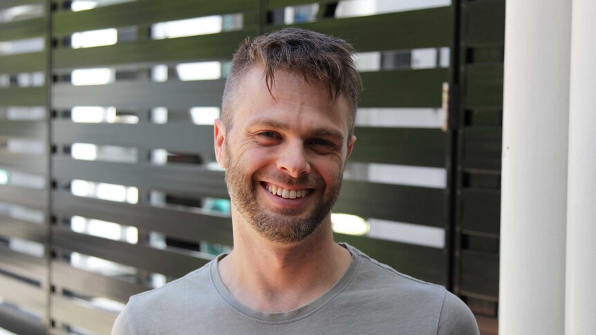 A young man smiles in a portrait.