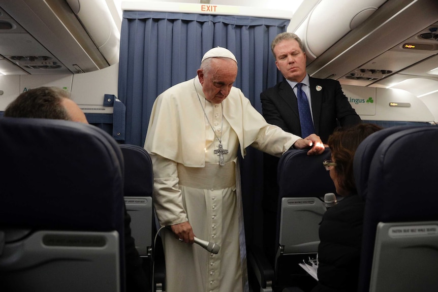 Pope Francis and Vatican spokesperson Greg Burke listen to a question during a press conference aboard a flight to Rome.