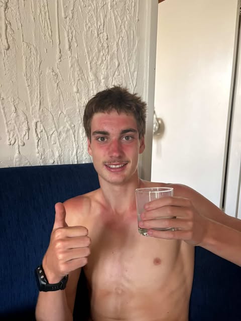 Um menino bebendo um copo de leite com o polegar para cima. 