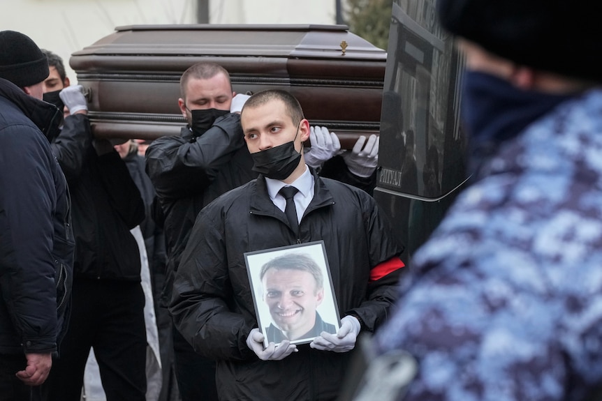 Workers carry the coffin and a portrait of Russian opposition leader Alexei Navalny.