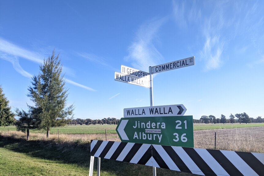 A road sign in front of a paddock points to Walla Walla in one direction, and Jindera and Albury in the other