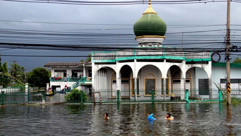 Children swim in front of a mosque surrounded by floodwater in Bangkok