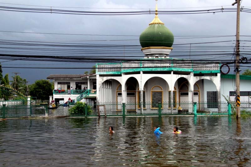 Children swim in front of a mosque surrounded by floodwater in Bangkok