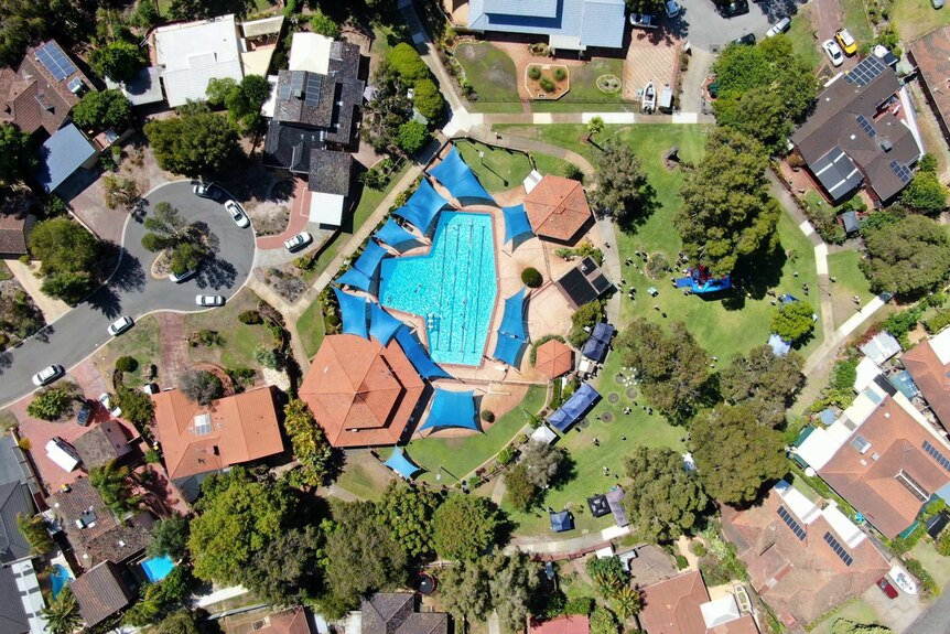 An aerial view of pool, park and home rooftops