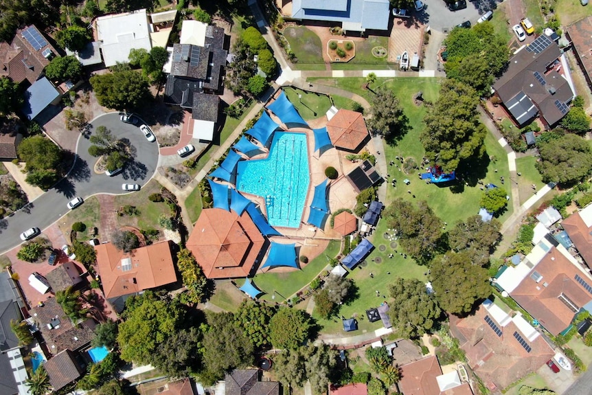 An aerial view of pool, park and home rooftops