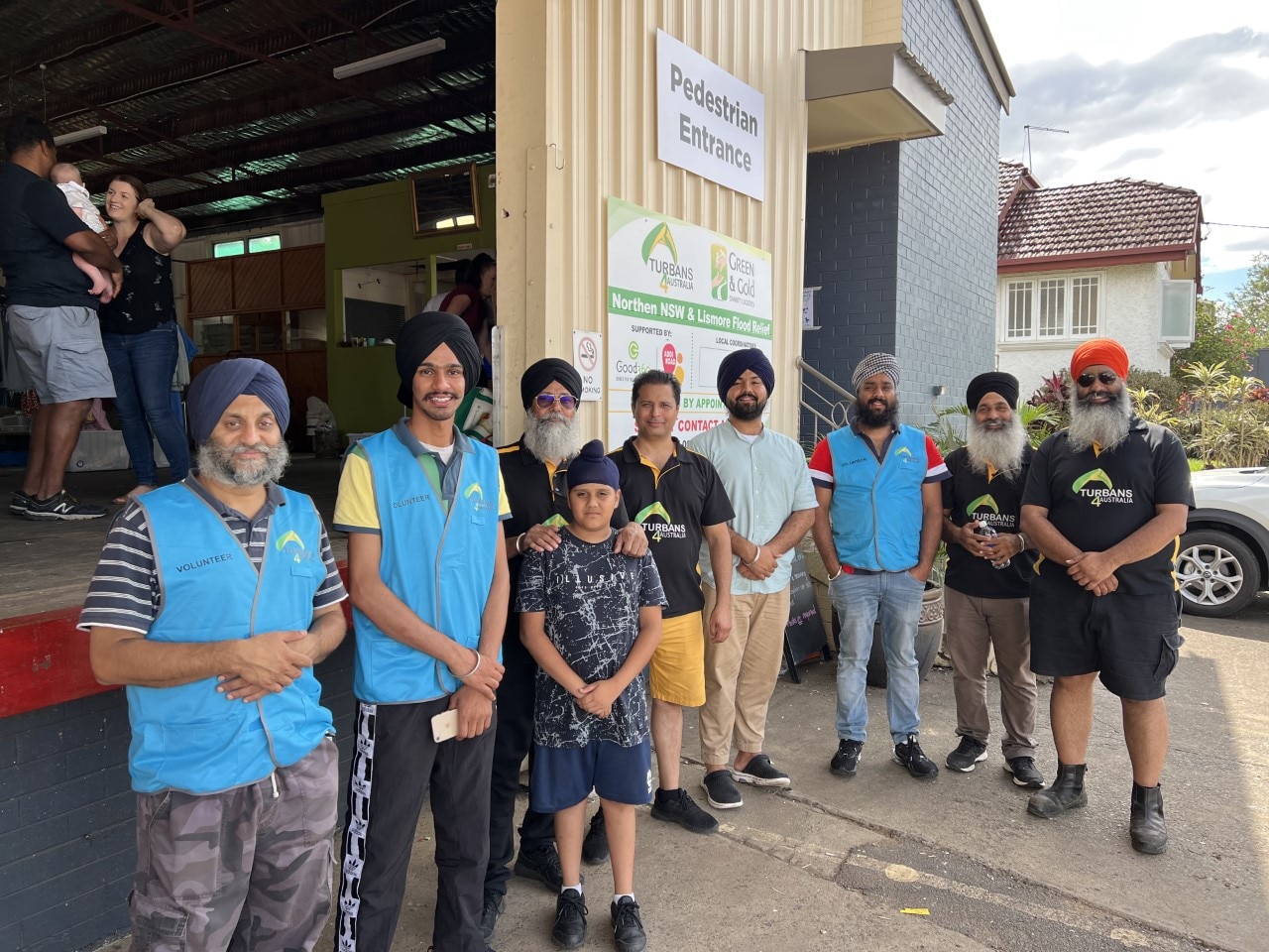 A group of Sikh men wearing turbans stand outside of a warehouse depot.