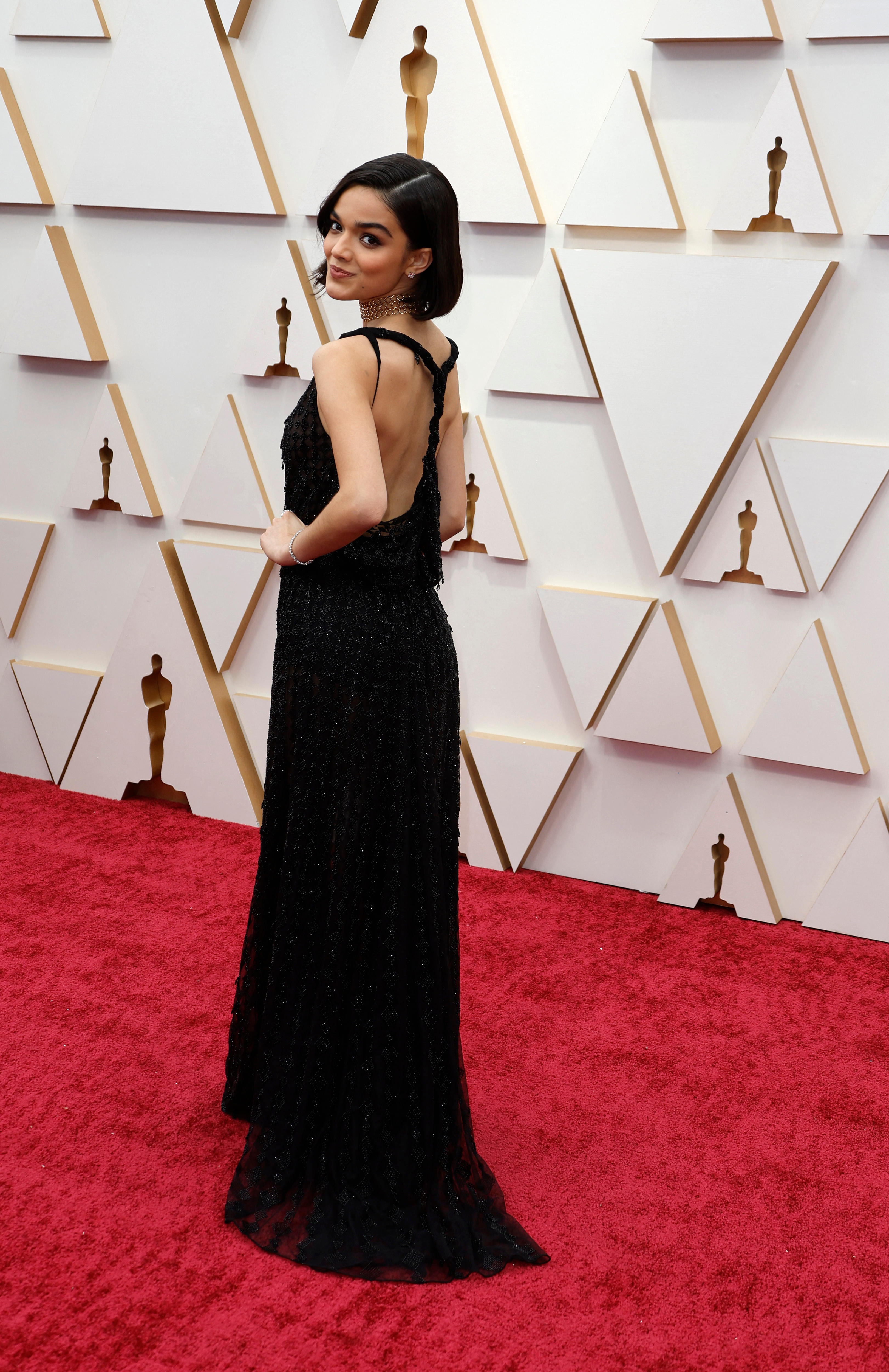 rachel zegler poses looking over her shoulder on the red carpet wearing a black gown