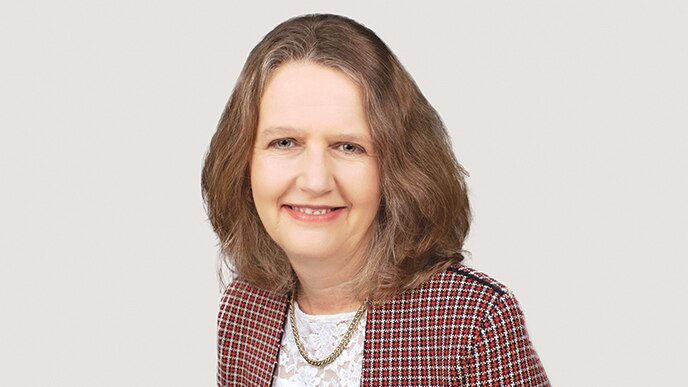 A psychologist, wearing professional clothing, smiles to camera