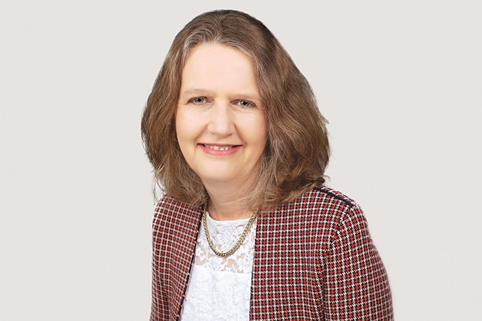 A psychologist, wearing professional clothing, smiles to camera