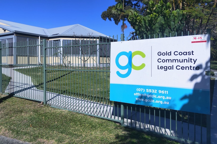 A blue, white and green sign in front of  building that reads Gold Coast Community Legal Centre