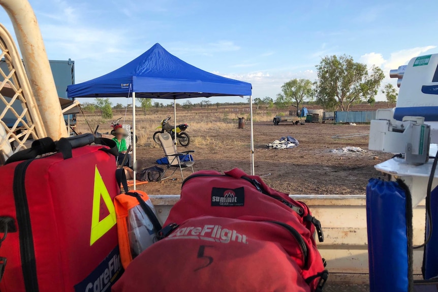 Swag on an outback plain, near where a rescue aircraft lies dormant.