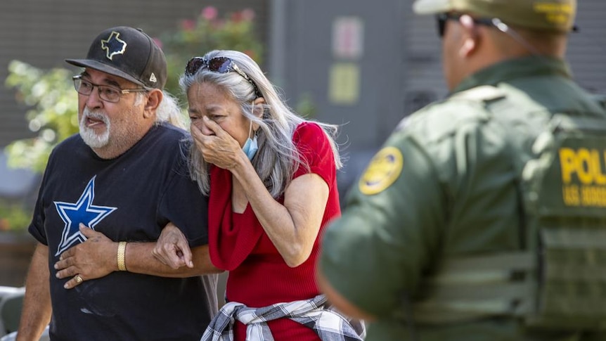A woman cries next to a man as she leaves the Uvalde Civic Center in Texas