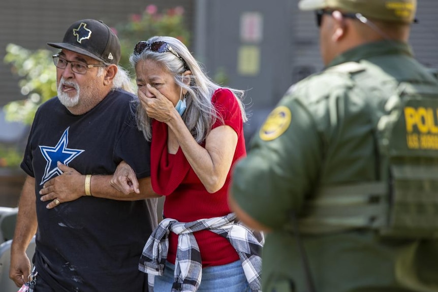 A woman cries next to a man as she leaves the Uvalde Civic Center in Texas