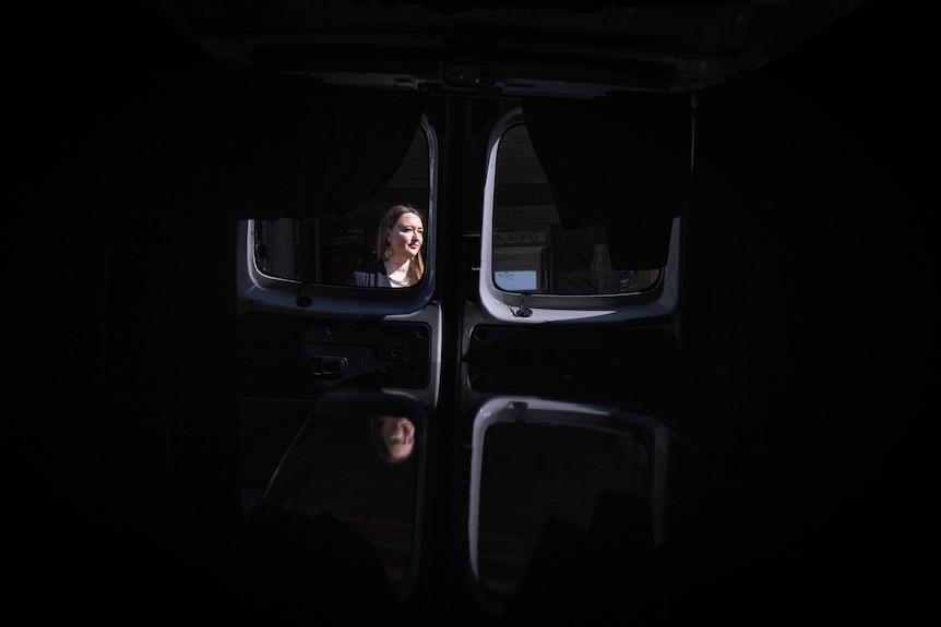 A woman is seen through the back window of a hearse