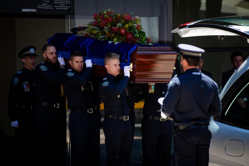 Six police officers carry a casket