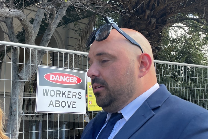 Photo of a man in a suit outside a construction site.