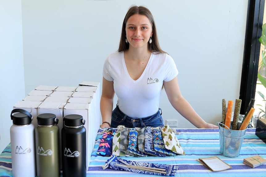 Jasmine Klimiuk stands in front of a table with reusable drink bottle and bees wax wraps.