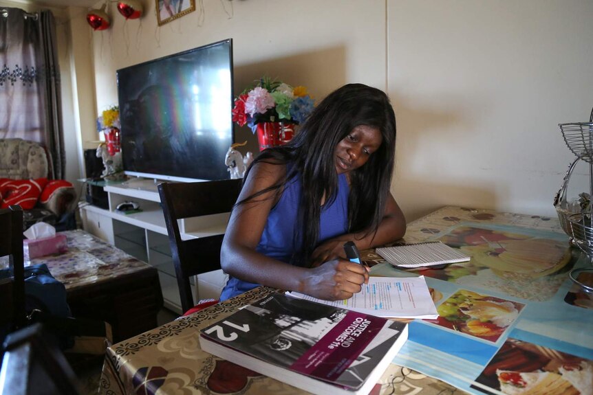 Ayan Macuach studies at a table in her home.