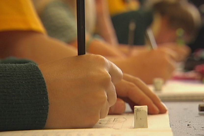 Close up of an unidentified primary school student writing on a desk, generic.