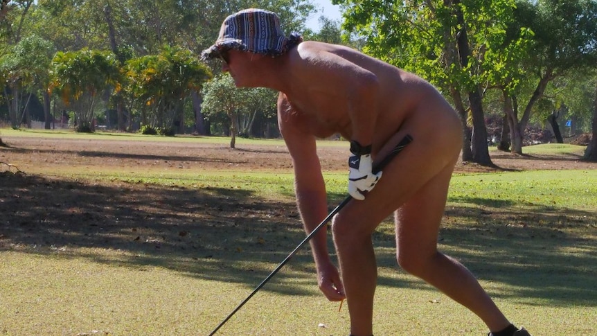 Man hold a golf club and bends over, wearing only a hat and shoes