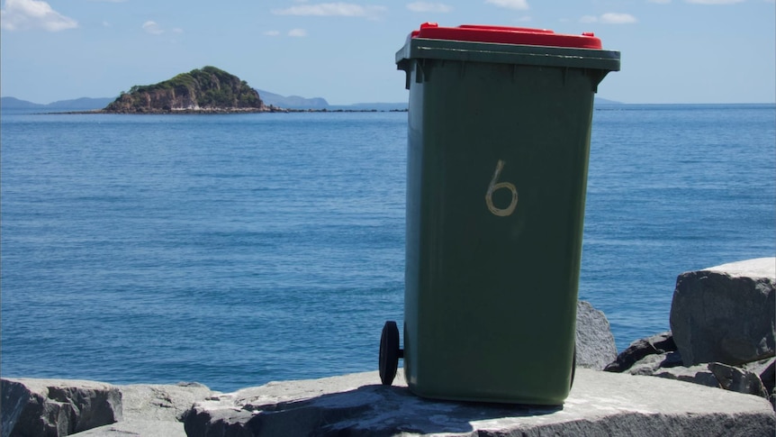 A normal garbage bin in front of the ocean