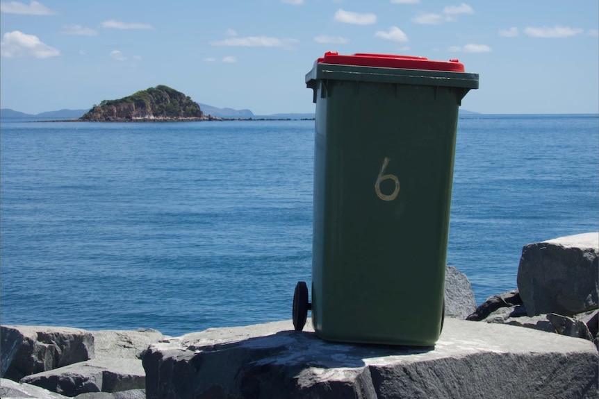 A normal garbage bin in front of the ocean