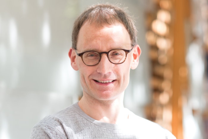 A portrait photo of a man in glasses smiling