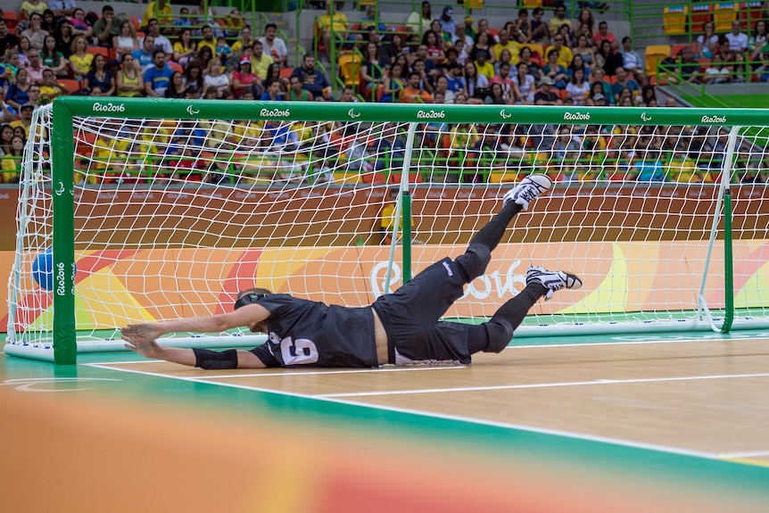 The ball goes into the net as a defender in goalball dives full length in a vain attempt to stop a goal.
