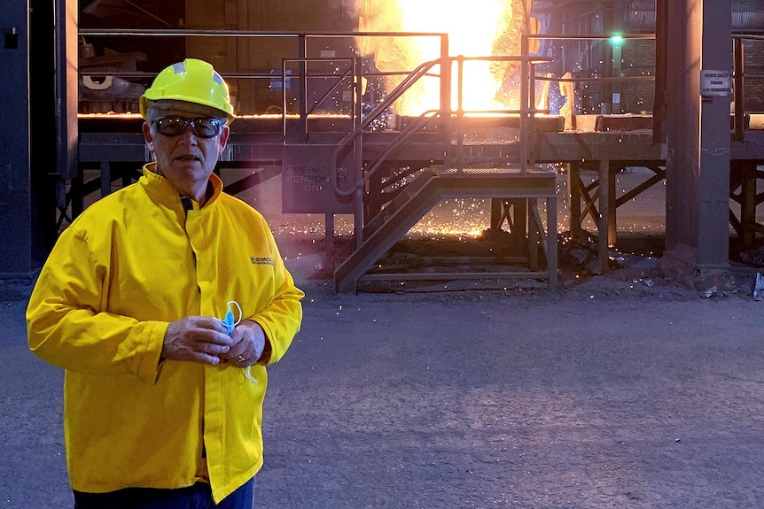 A man in protective gear stands in front of a silica plant