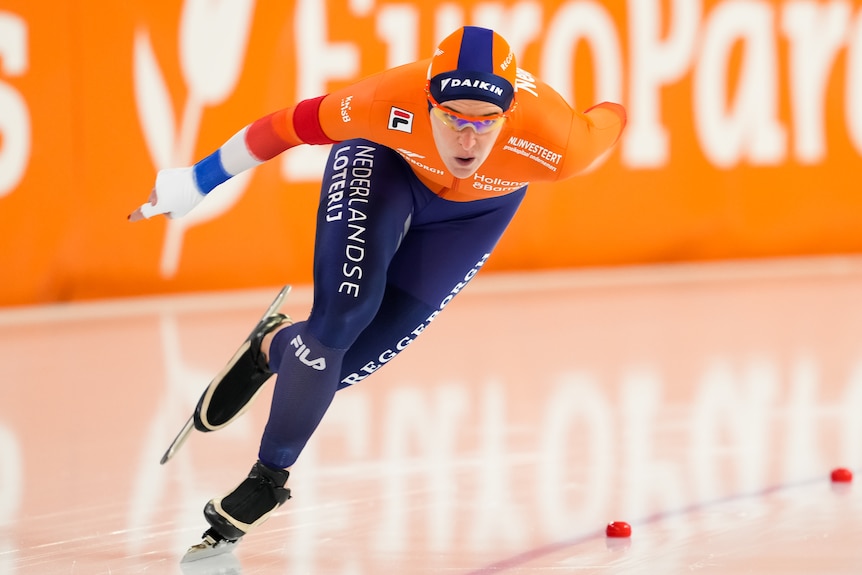 Ireen Wust skates around a bend looking forward with her right arm out to the side