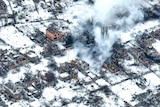 An aerial view of Bakhmut shows destroyed houses smouldering in the snow.