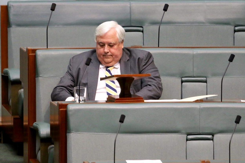 Clive Palmer looks downwards as he sits the House of Representatives Chamber.