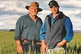 Two men standing in a field of wheat.