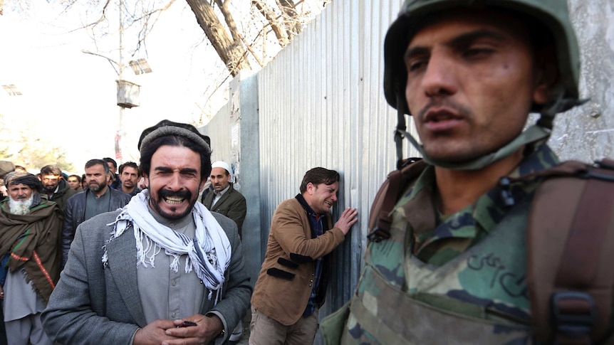 Afghan men cry at the scene of the attack on a military hospital in Kabul, Afghanistan.
