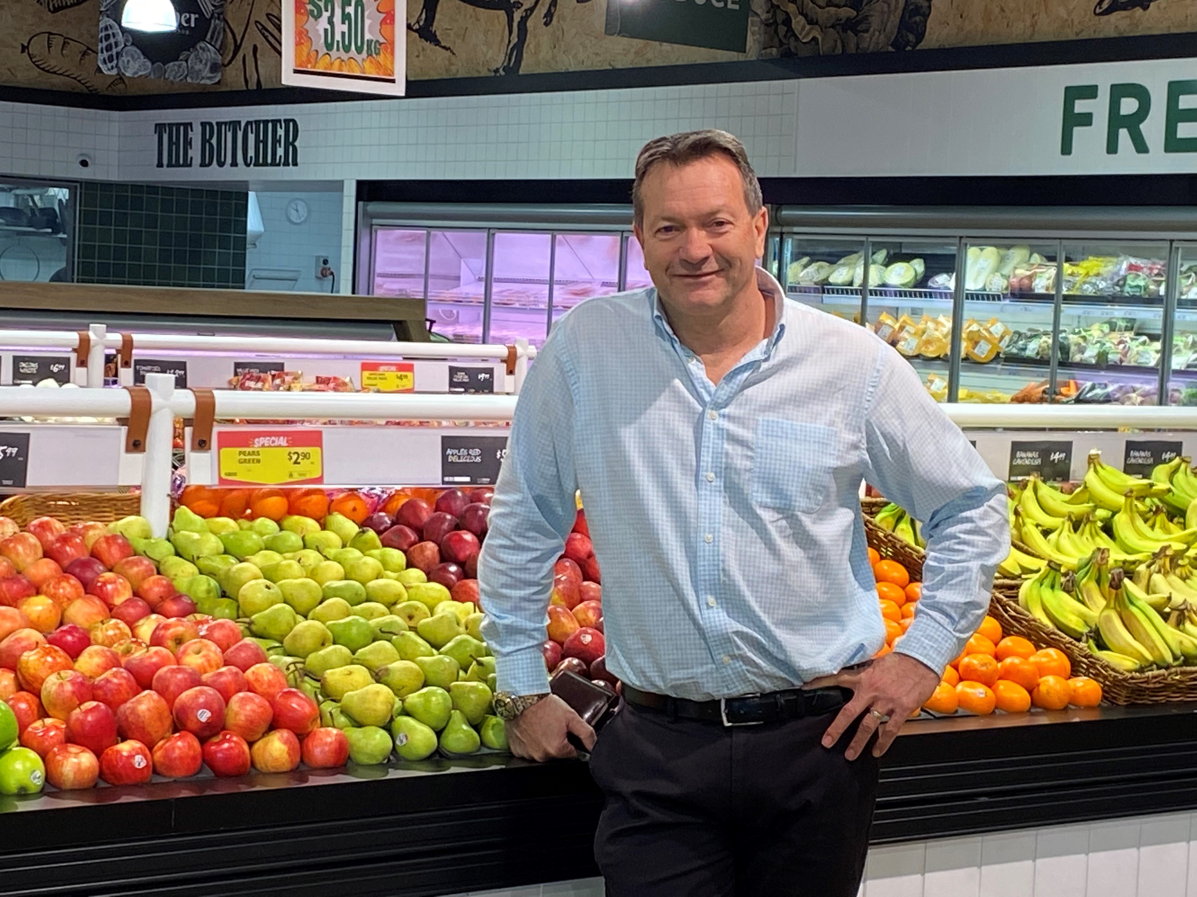 Man in business shirt, in front of fresh produced, looking at camera