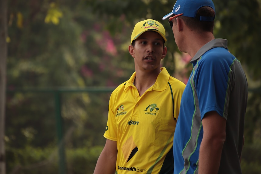 Two players talk to each other, one player in yellow and one in blue kit.