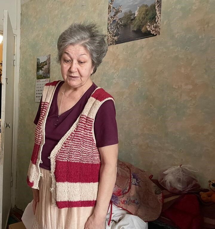 An older woman with cropped grey hair looks down 