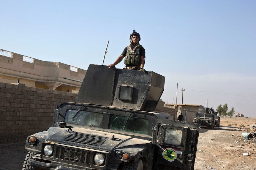 An Iraqi special forces soldier stands atop a Humvee in the village of Bazwaya.