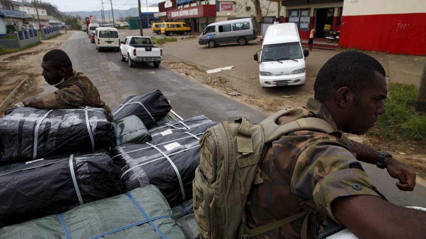 Military personnel ride on a truck carrying aid supplies for cyclone-hit Vanuatu