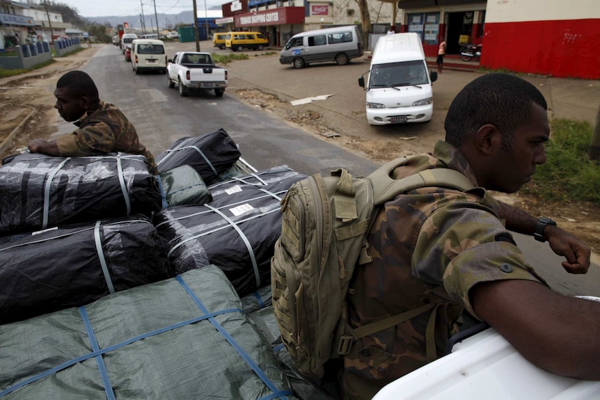 Military personnel ride on a truck carrying aid supplies for cyclone-hit Vanuatu