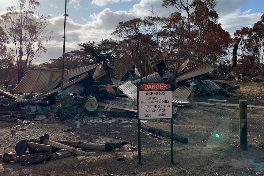 A pile of rubble with a sign warning of asbestos